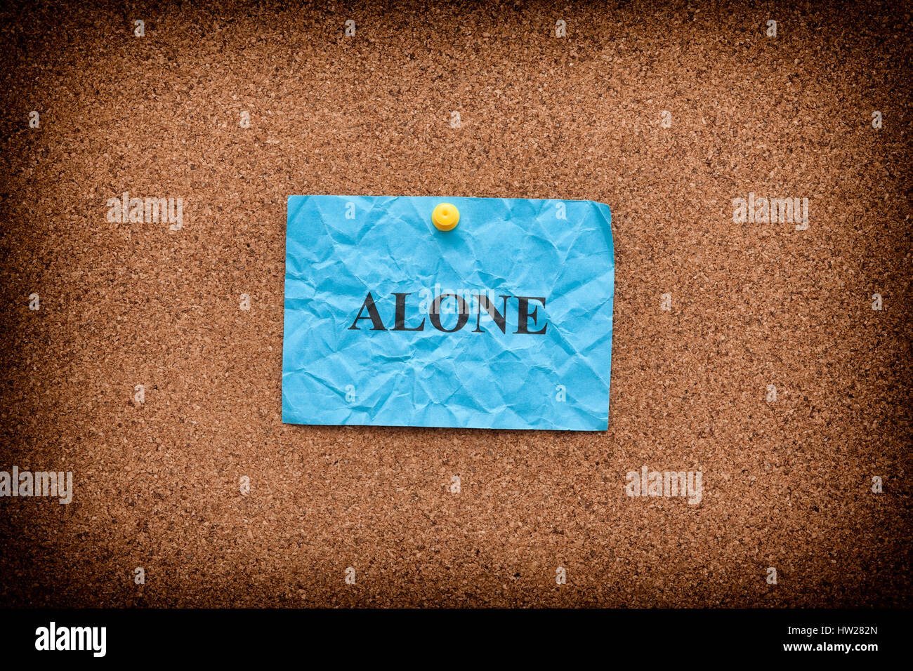 Blue crumpled paper with word Alone on a cork board. Close up Stock ...