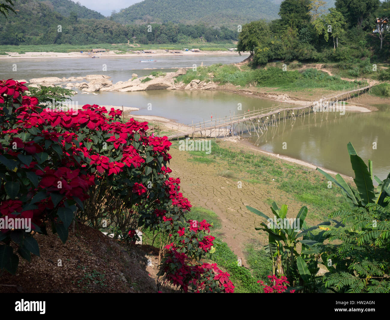 A flimsy looking footbridge over a tributary of the Mekong River. Stock Photo