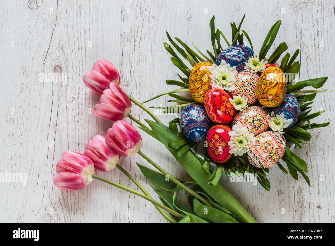 Easter Background with easter eggs and pink tulips on light wooden ...