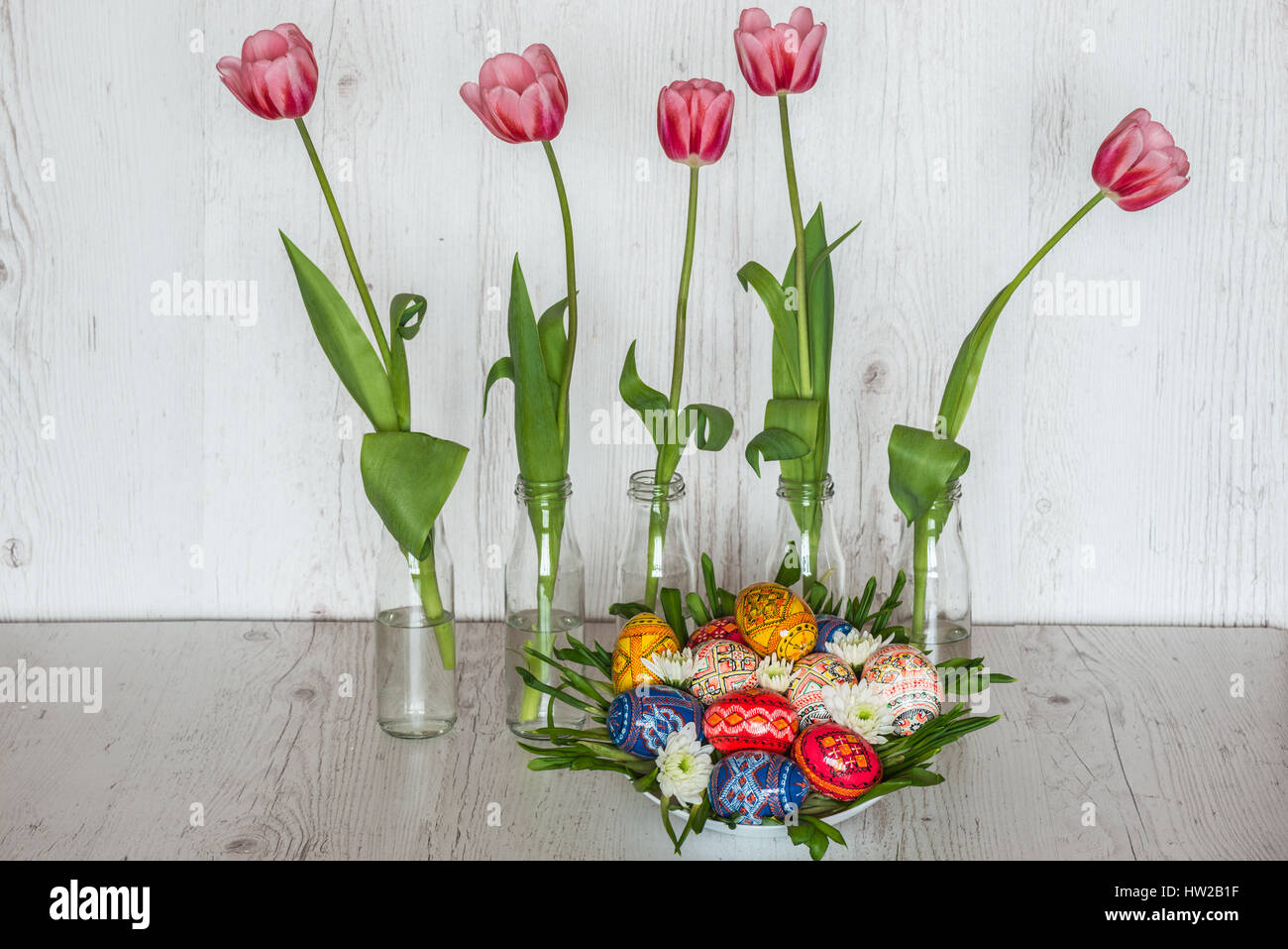 Easter Background with easter eggs and pink tulips in glass bottles on ...