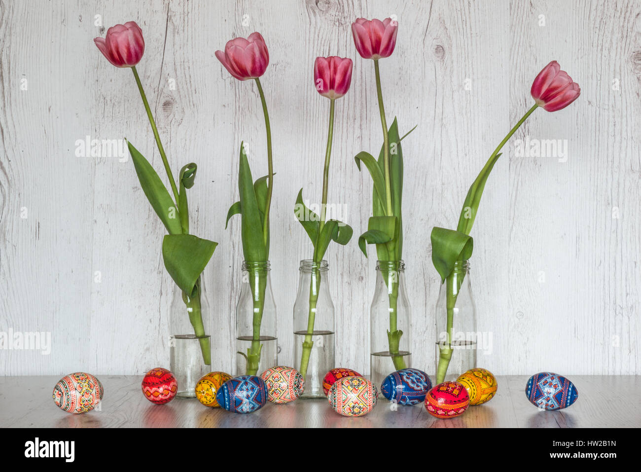 Easter Background with easter eggs and pink tulips in glass bottles on ...