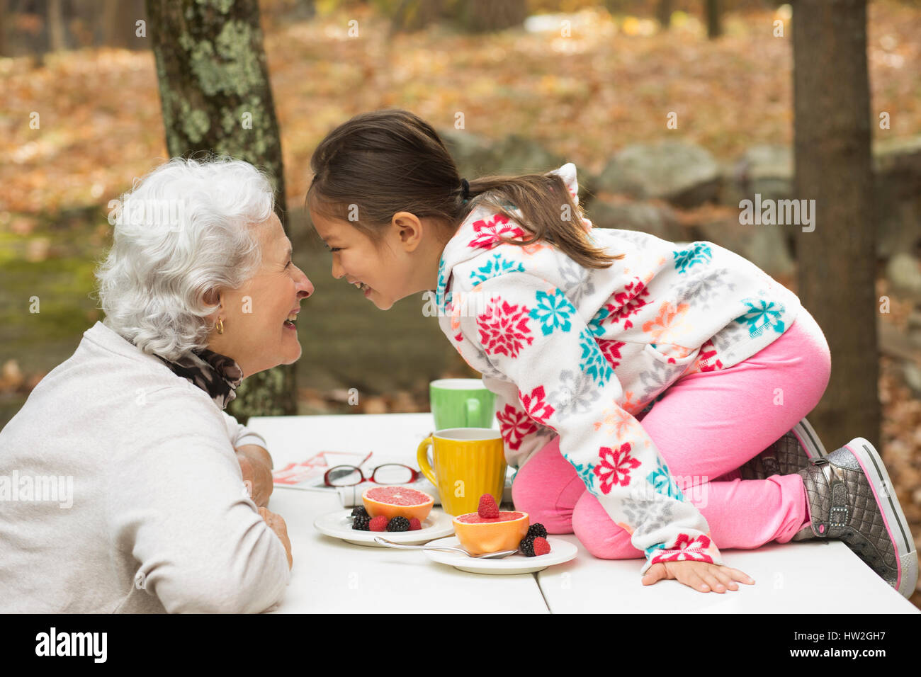 Grandmother and granddaughter playing at breakfast table outdoors Stock Photo