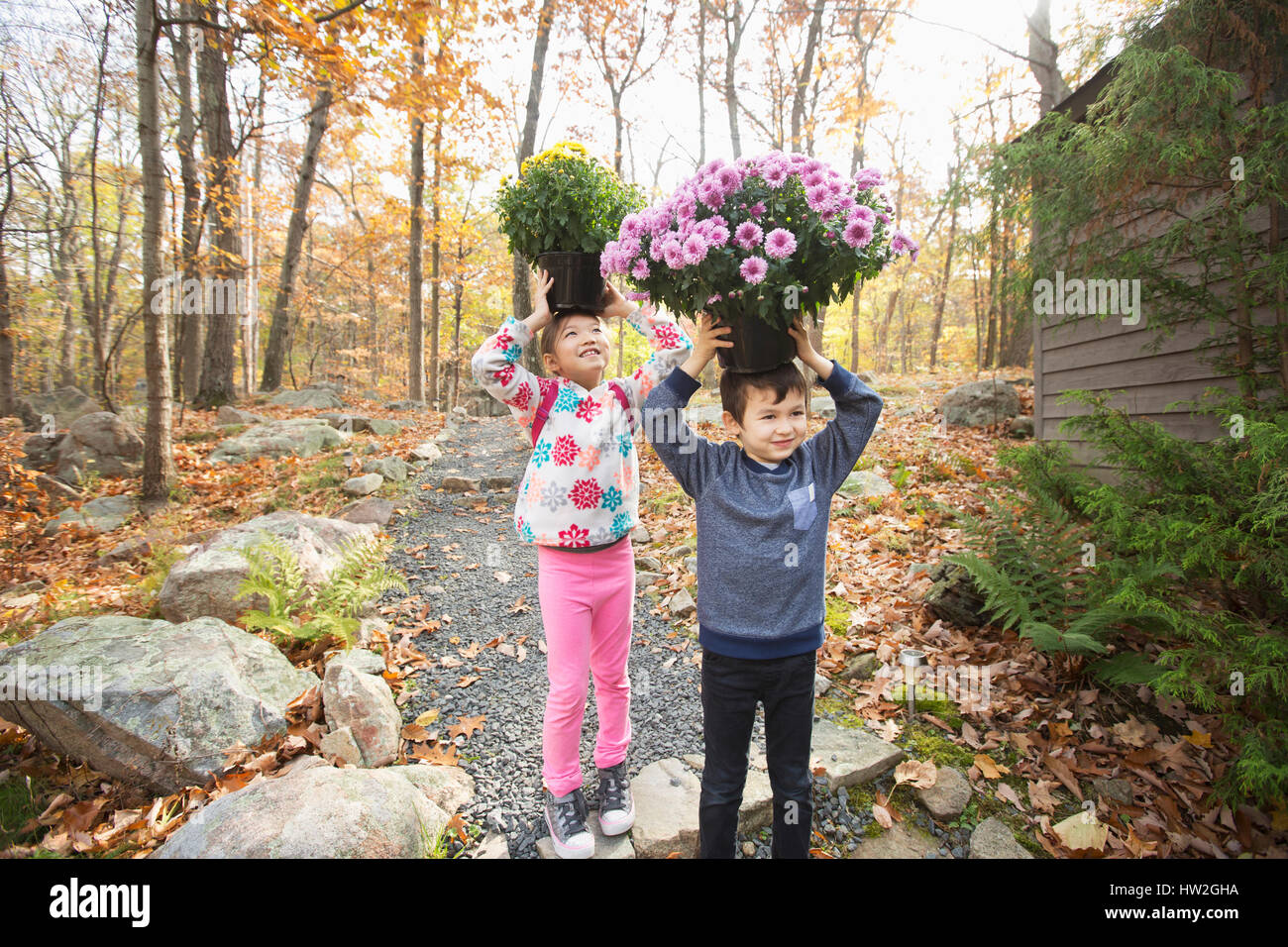 Mixed Race brother and sister balancing flowers on heads Stock Photo
