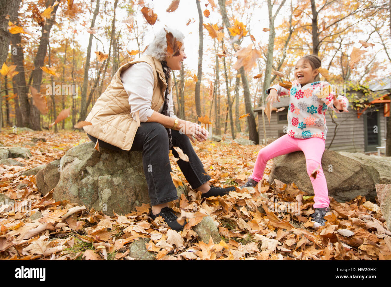 Grandmother and granddaughter playing with autumn leaves Stock Photo