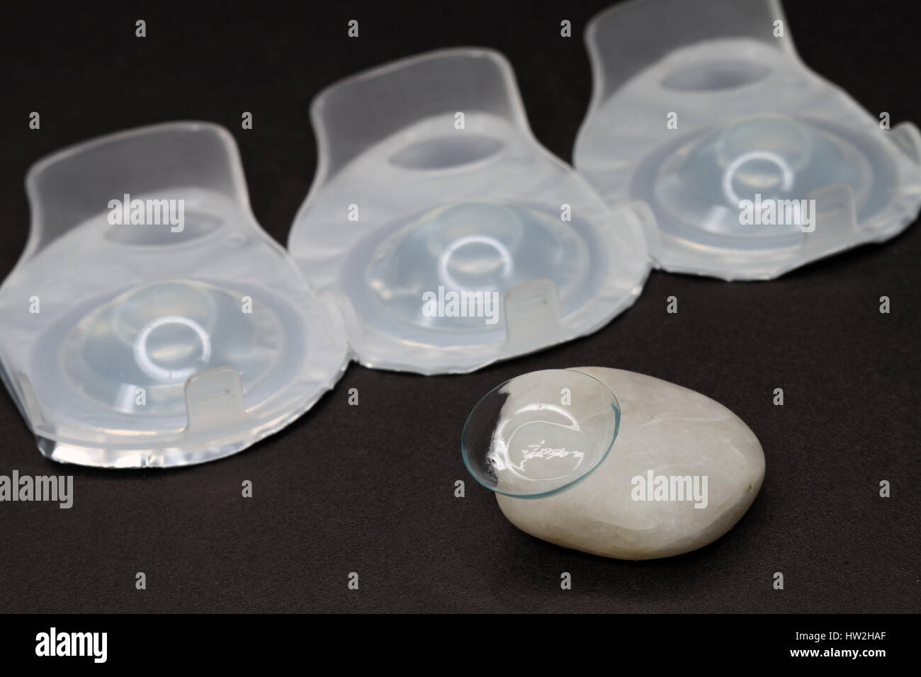 Contact lens on a piece of a granite-combination of fragility and hardness. Packings with new lenses. Stock Photo