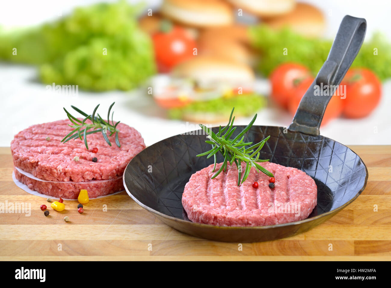 Raw burger patty in an iron frying pan ready to fry, some burger