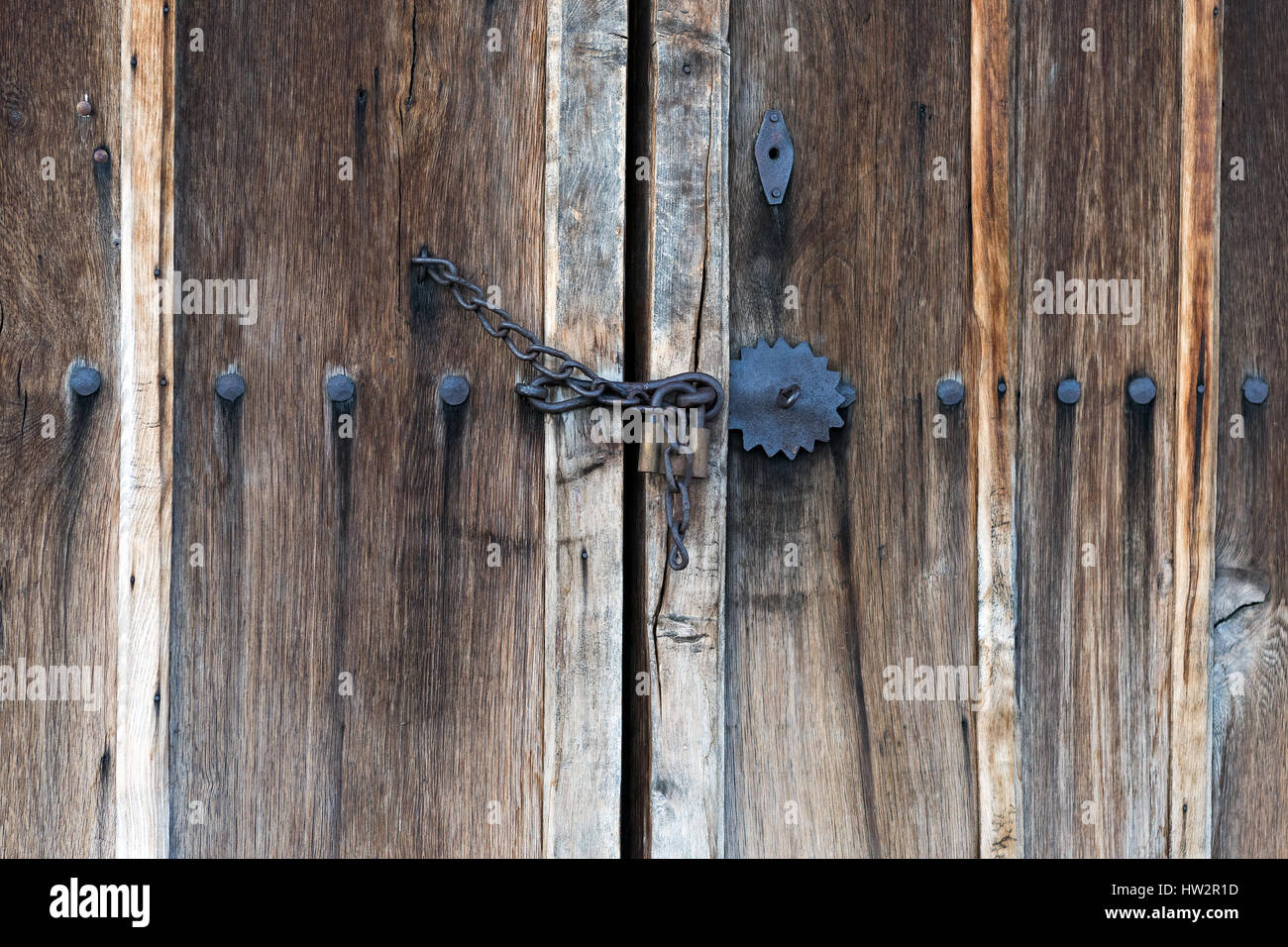 Chain locked wooden door with big iron nails and metal ornaments Stock Photo