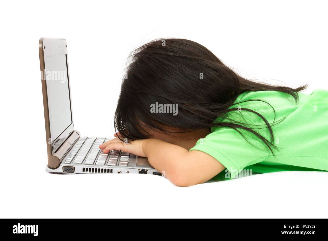 Chinese little girl sleep in front of a laptop in plain isolated white background. Stock Photo
