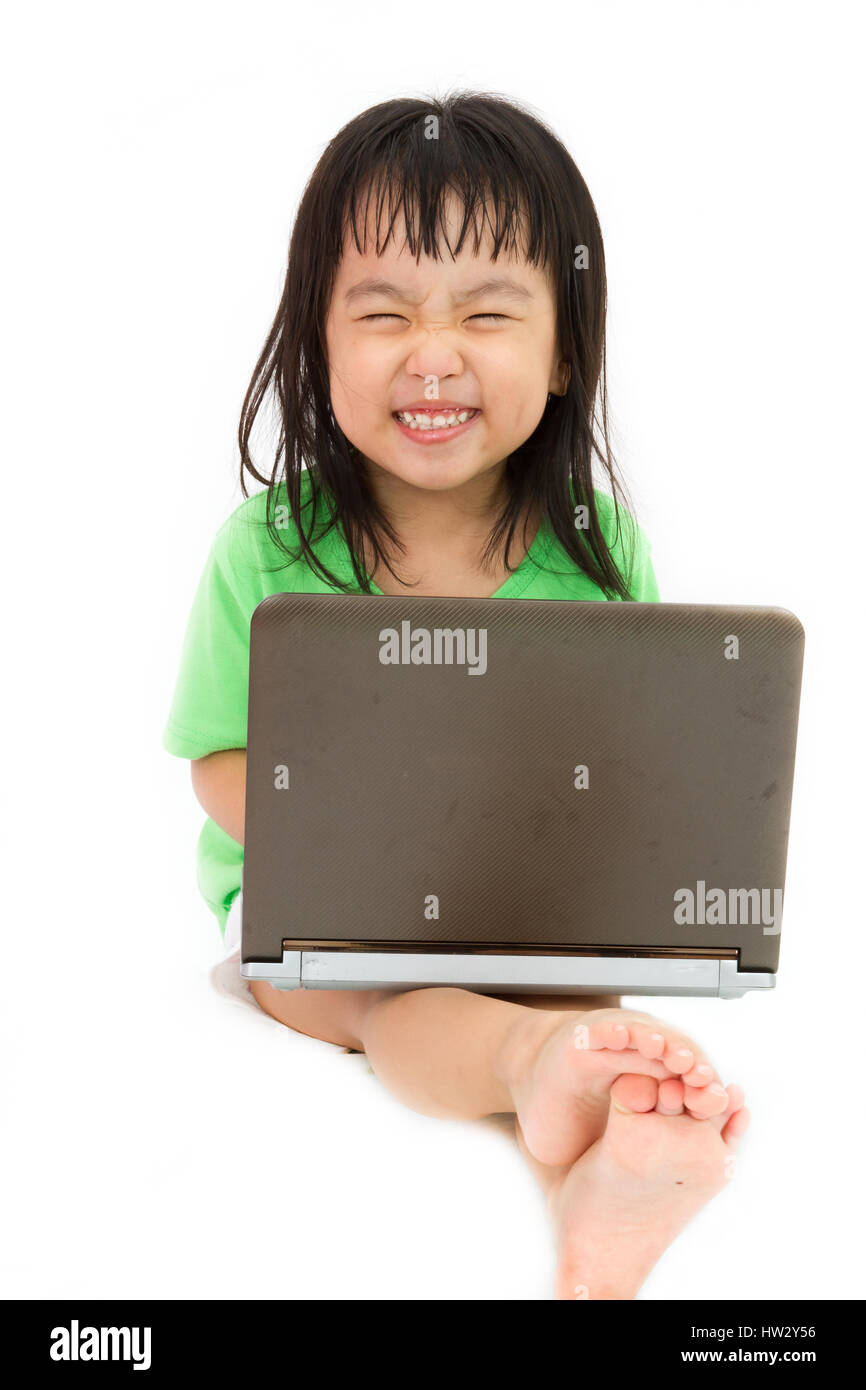 Chinese little girl sitting on floor with laptop in plain isolated white background Stock Photo