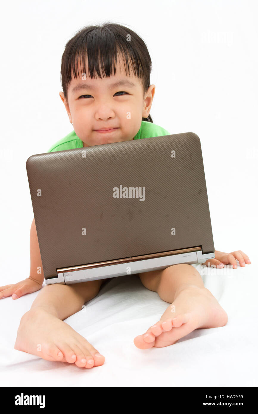 Chinese little girl sitting on floor with laptop in plain isolated white background Stock Photo