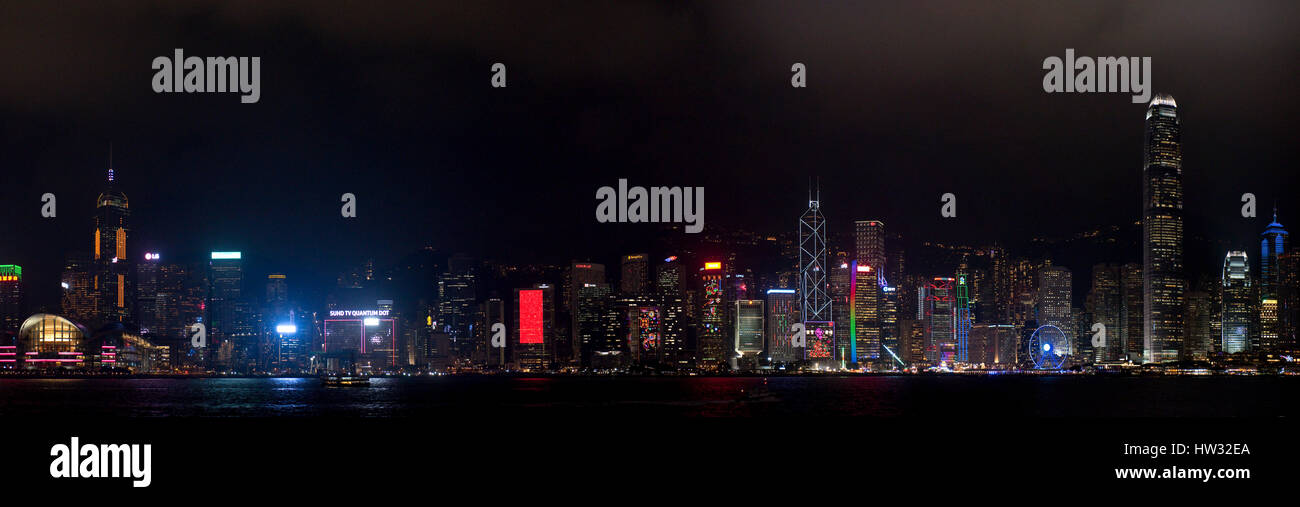 A 3 picture stitch panoramic colourful cityscape view of the buildings along Hong Kong Island from the Kowloon Public Pier at night. Stock Photo