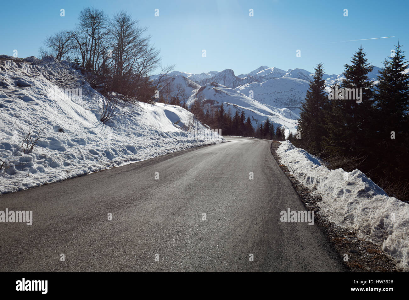 Empty mountain road descent on Alps, blue sky in a sunny day Stock Photo