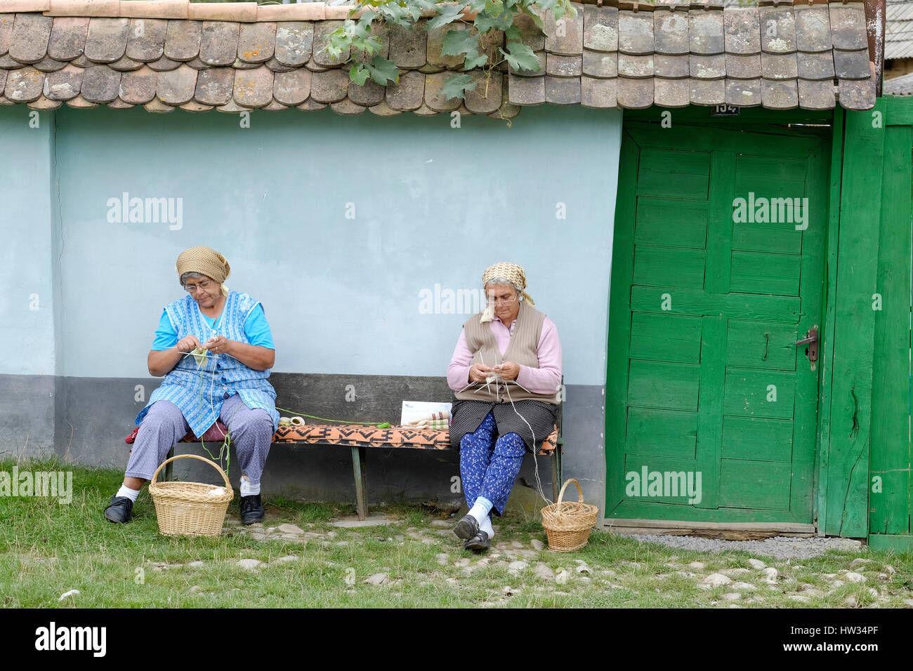 Two old women knitting socks in the town of Viscri, Romania. Viscri is a UNESCO World Heratige Site. Stock Photo