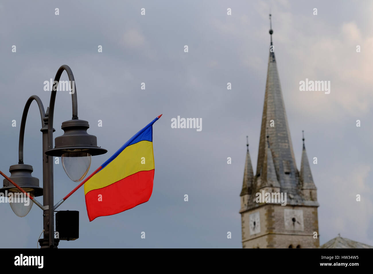 Romanian Flag and the steeple of the Reformed Church in the city center of Turda, in Cluj County, Romania. Stock Photo