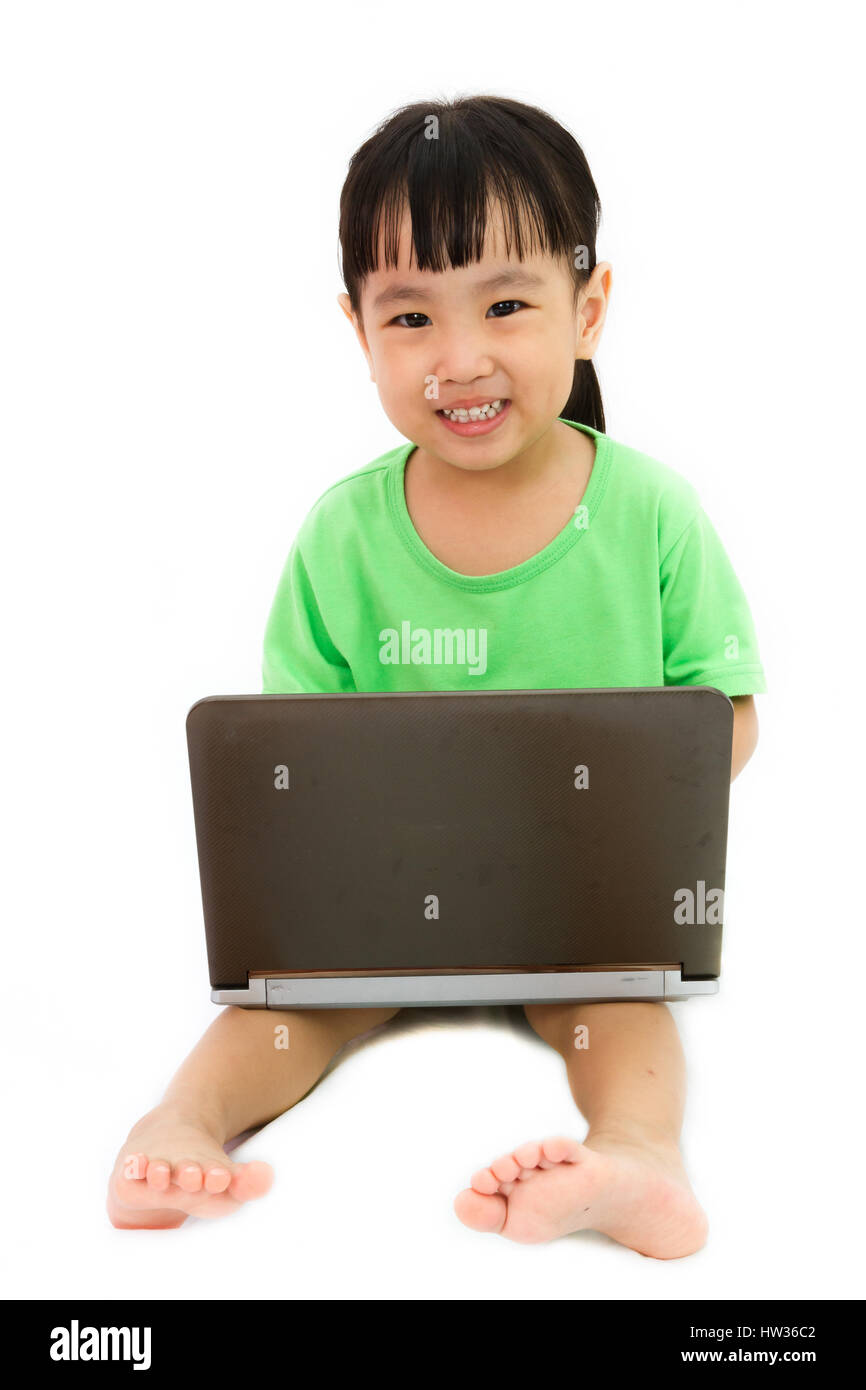 Chinese little girl sitting on floor with laptop in plain isolated white background Stock Photo