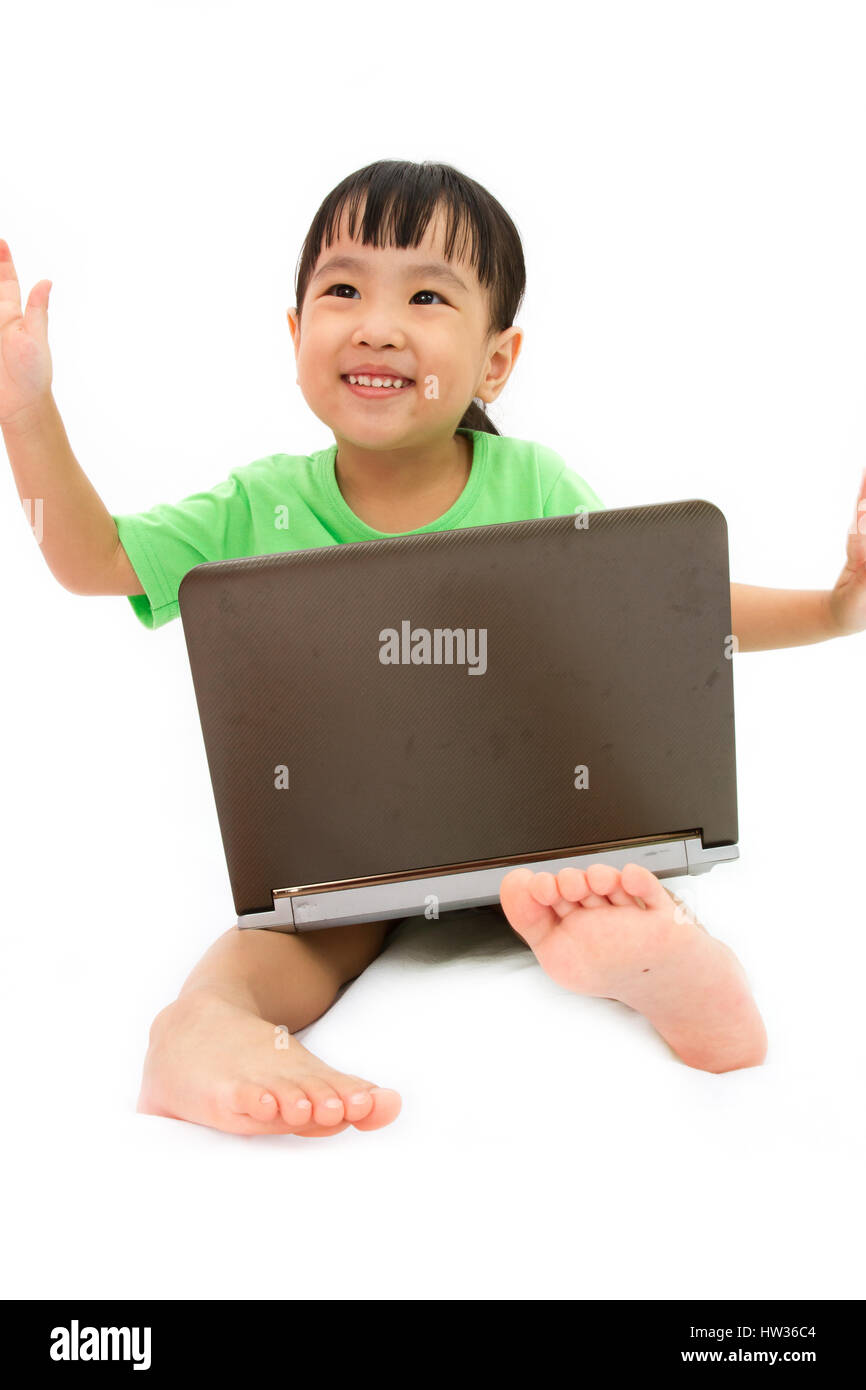 Chinese little girl sitting on floor with laptop in plain isolated white background Stock Photo