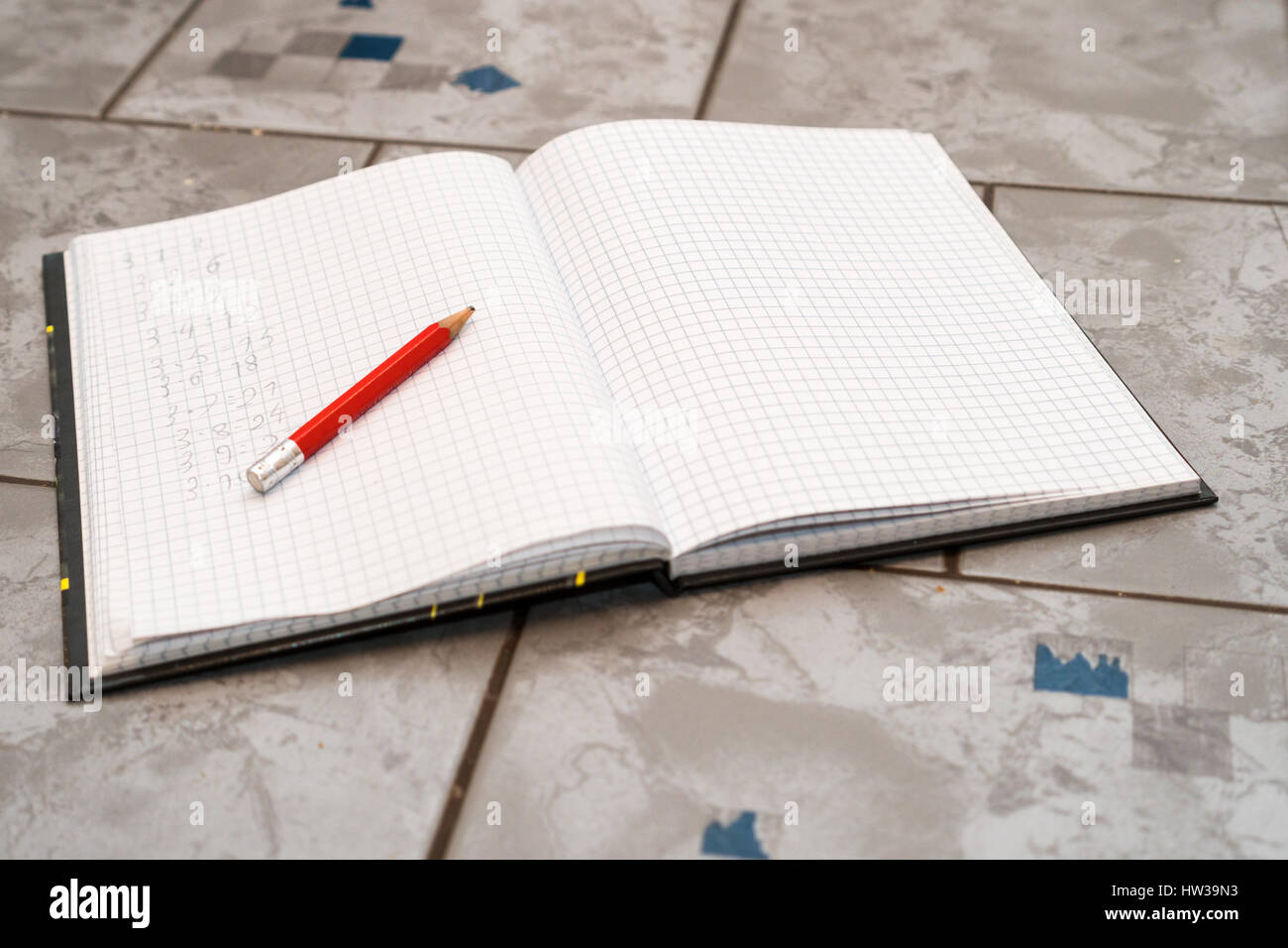 notebook in mathematics with handwriten exercise and a pencil on ceramic surface desk Stock Photo