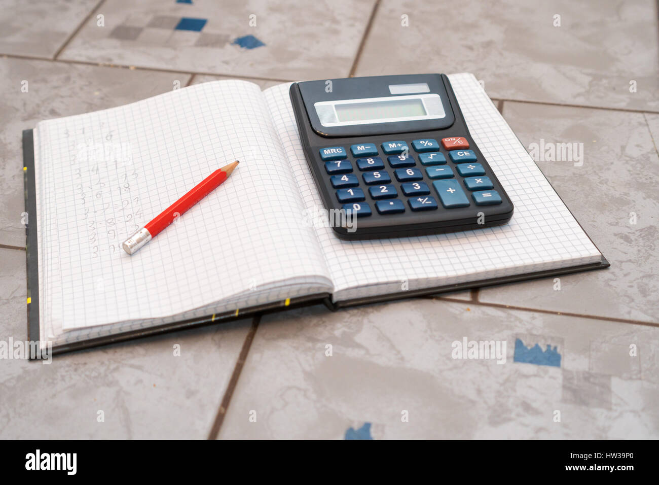 notebook in mathematics with handwriten exercise and a pencil and black calculator on ceramic surface desk Stock Photo