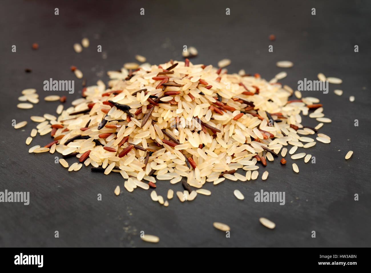 mixed rice, long grain basmati, red and wild, small pile on black slate ...