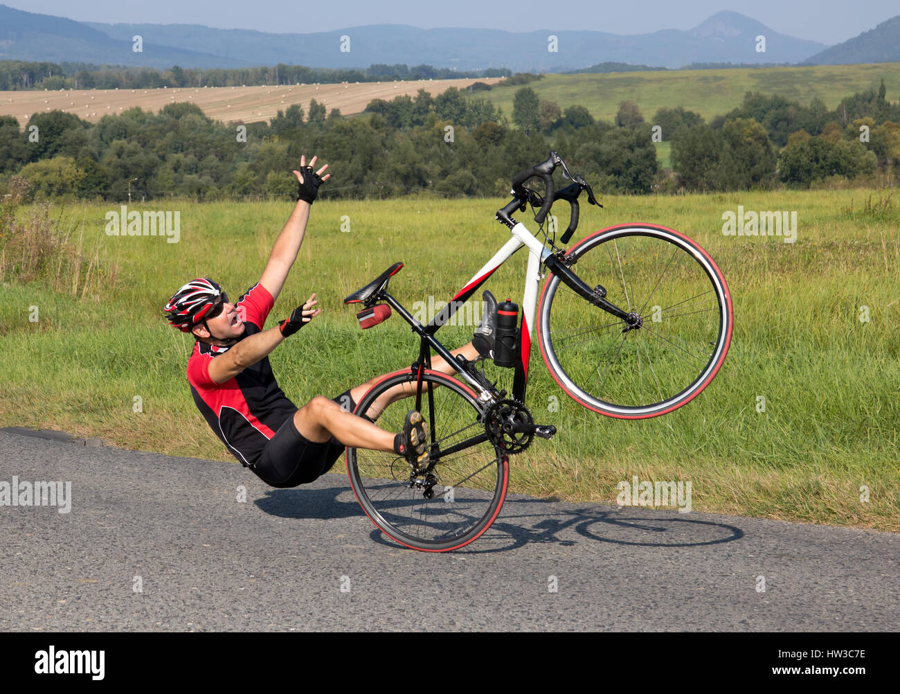 Cyclist falls off the bike on the asphalt road. Accident man in sports. Biker falls on his back while riding a road bike. Accident from acceleration. Stock Photo