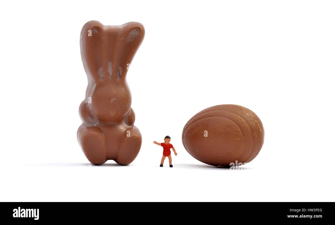A miniature figurine boy standing next to a chocolate bunny Stock Photo