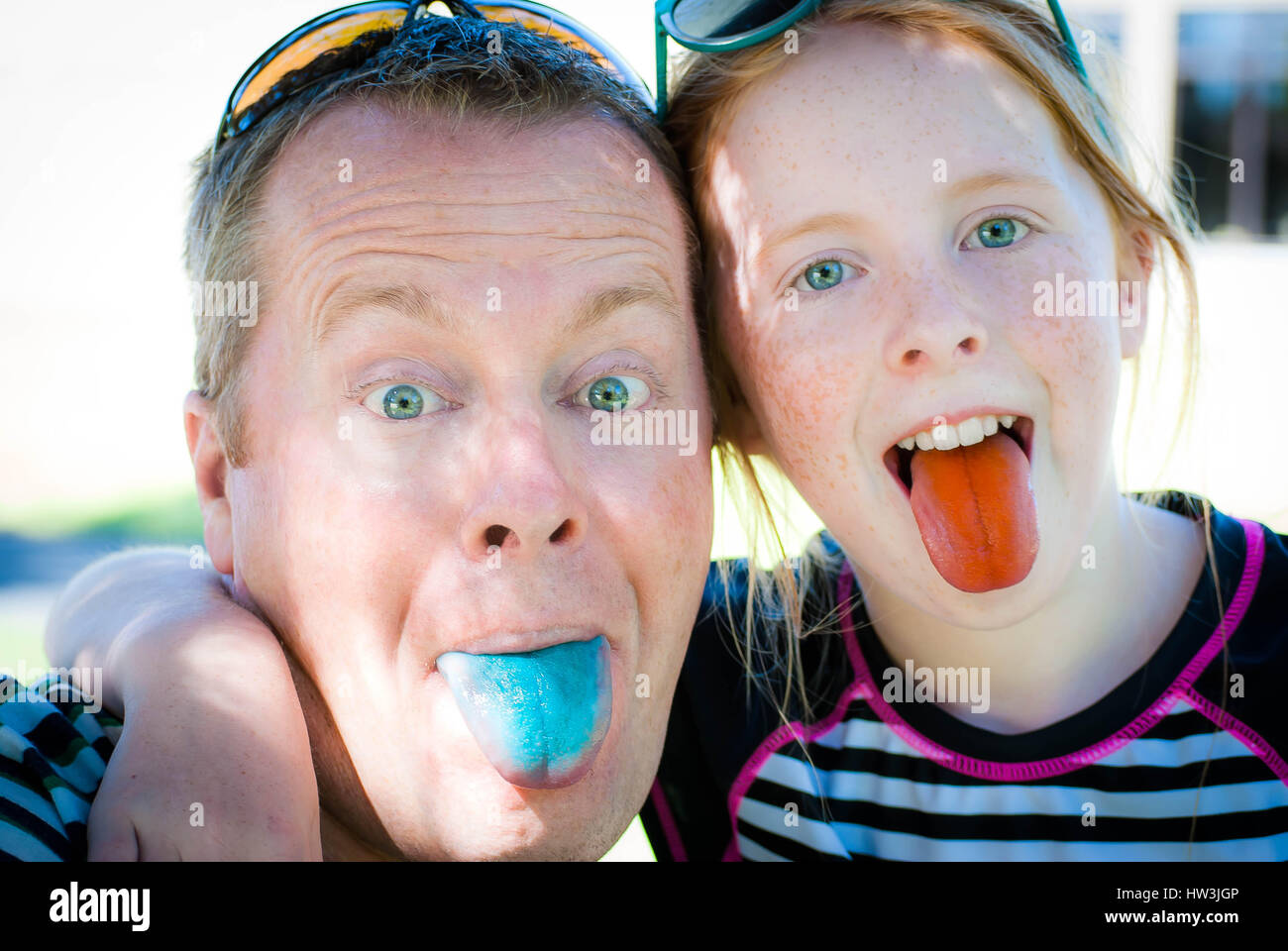 Father and daughter sharing a silly smile, showing their candy dyed tongues. Stock Photo
