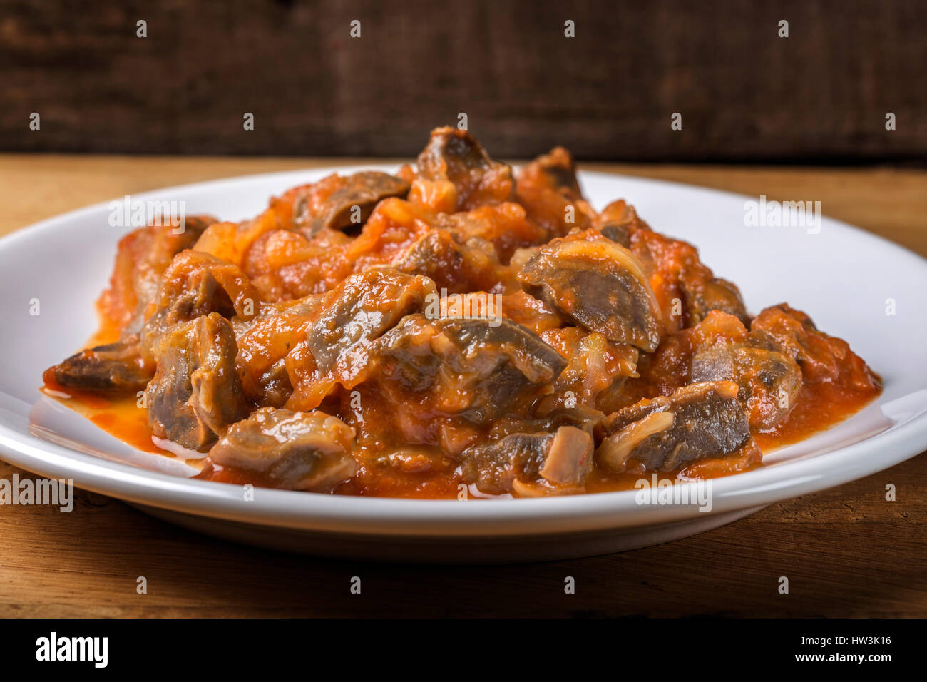 Chicken gizzard stew on plate on wooden rustic background Stock Photo