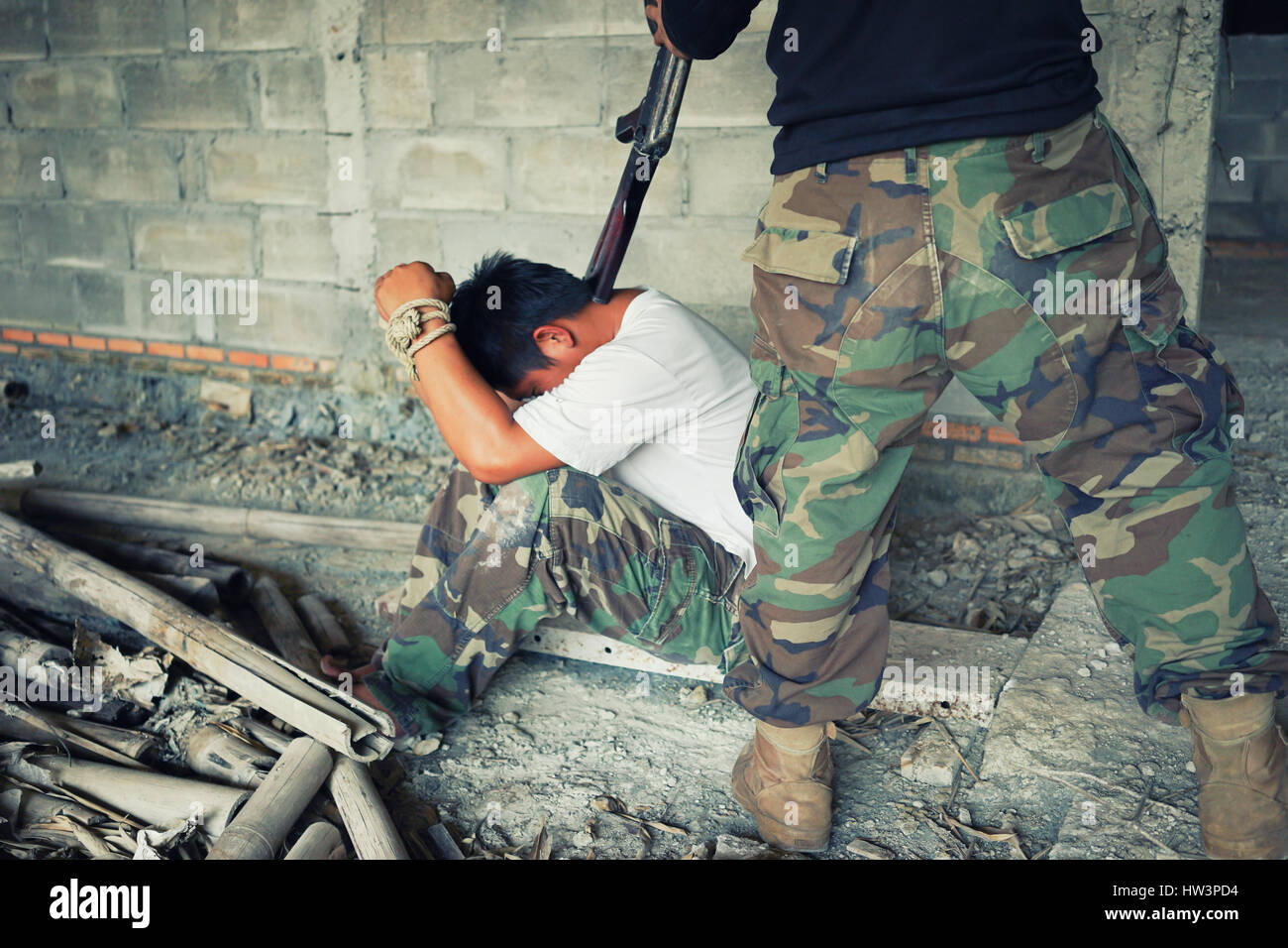 Terrorist in balaclava threatening with gun to man abducted Stock Photo