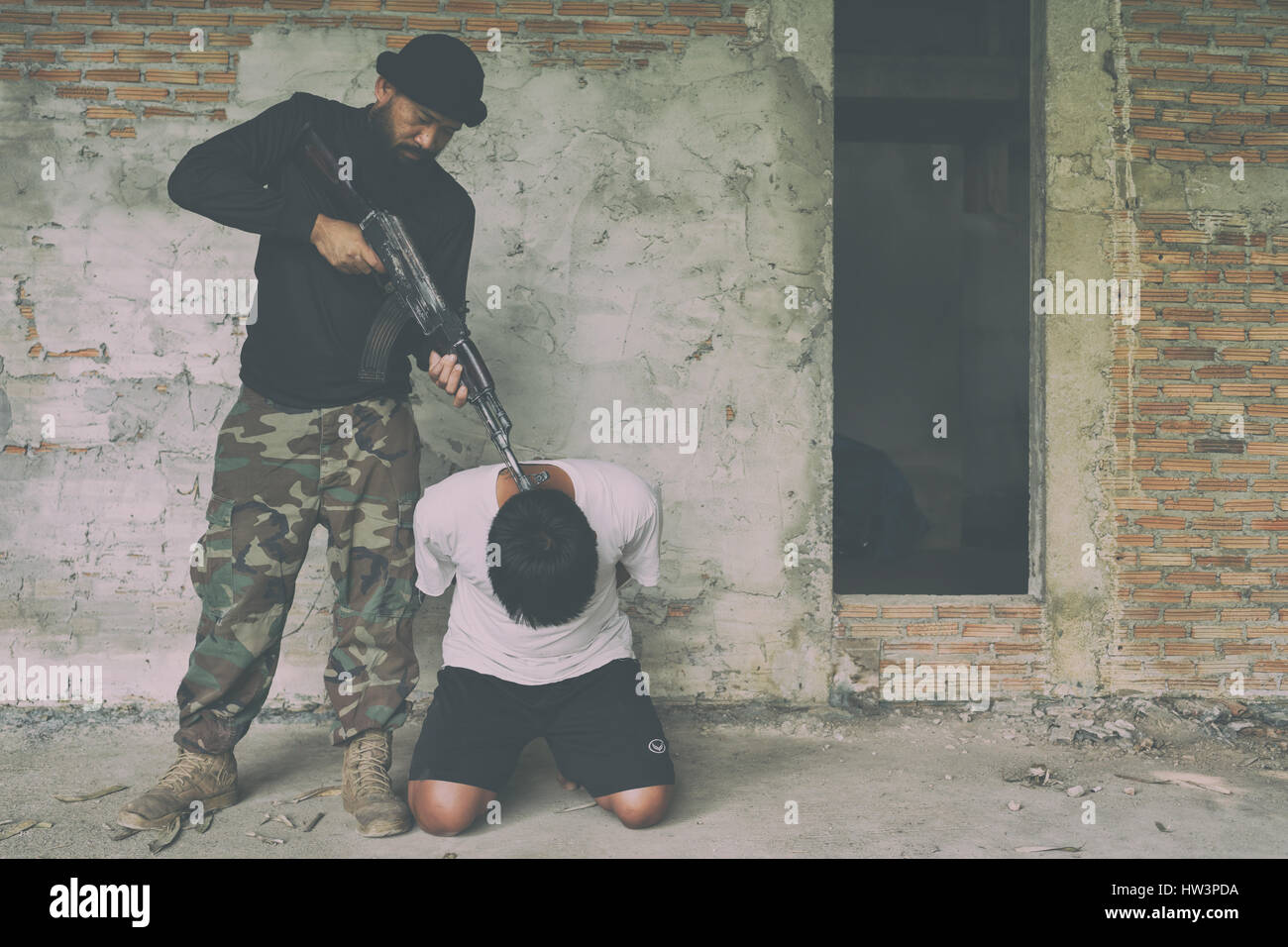 Terrorist in balaclava threatening with gun to man abducted Stock Photo