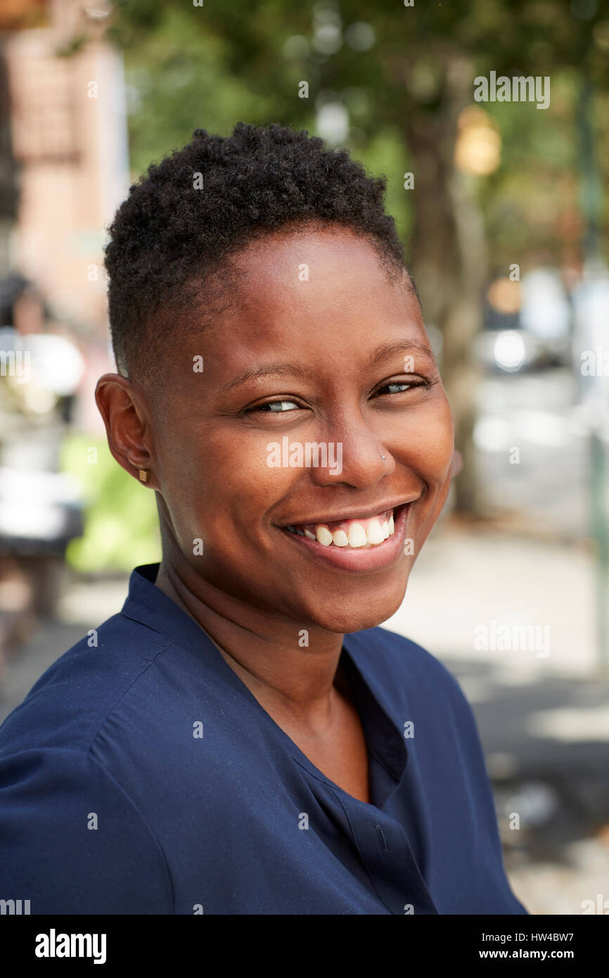 Black woman smiling on city sidewalk Stock Photo