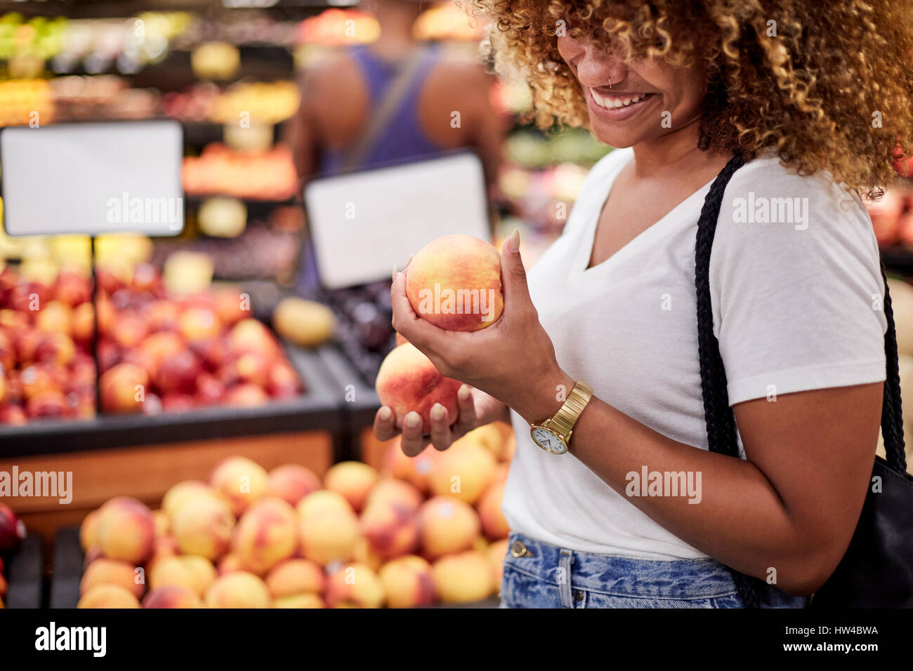 Black woman examining peaches in grocery store Stock Photo