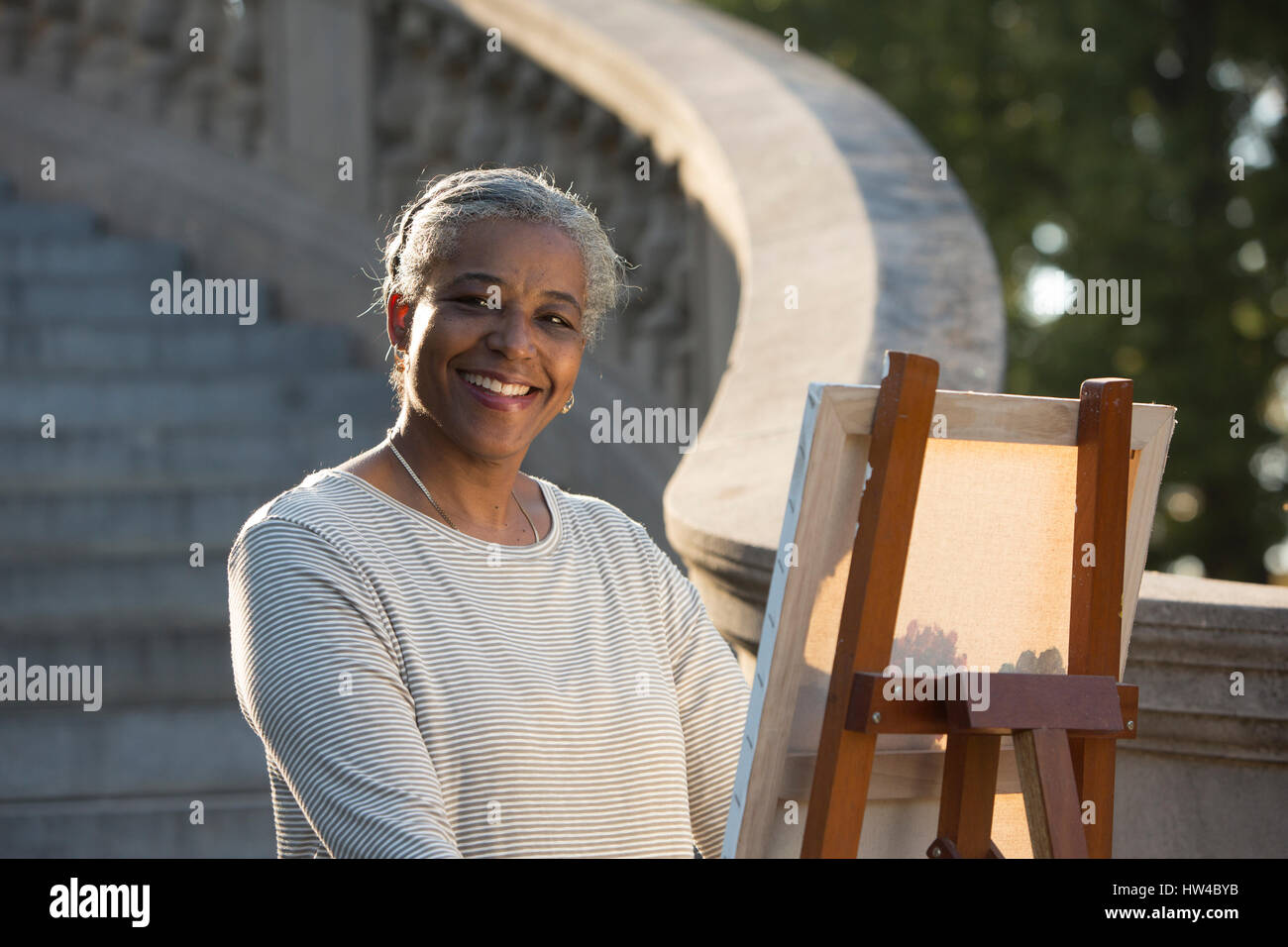 Black woman painting on canvas near stone staircase Stock Photo