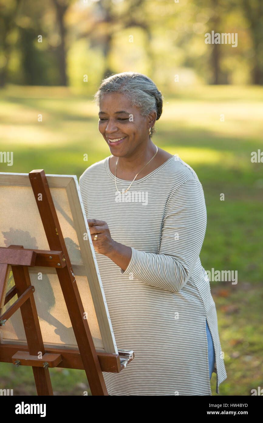 Black woman painting on canvas in park Stock Photo