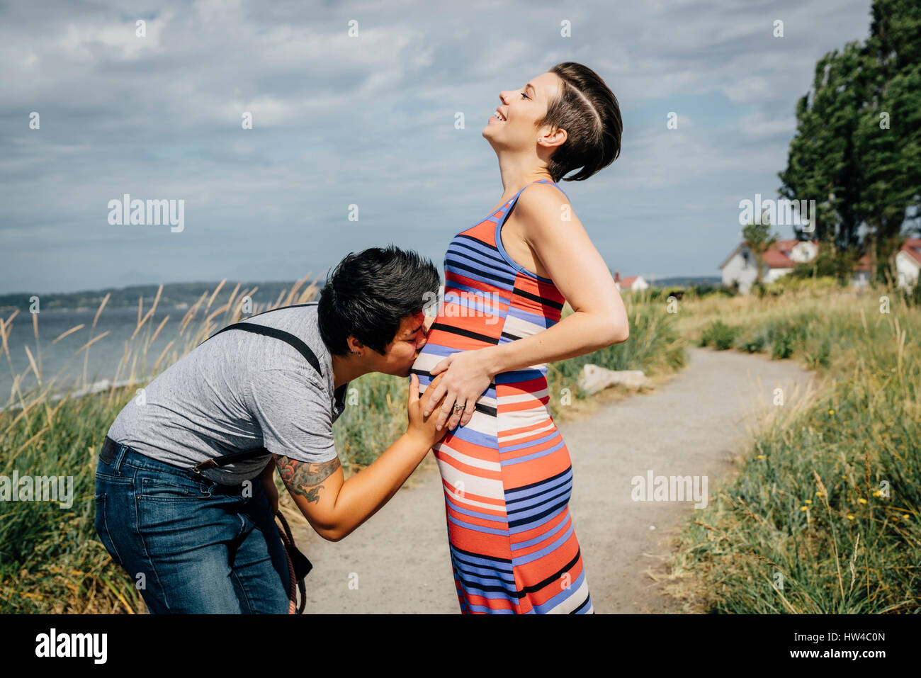Woman kissing belly of expectant mother Stock Photo