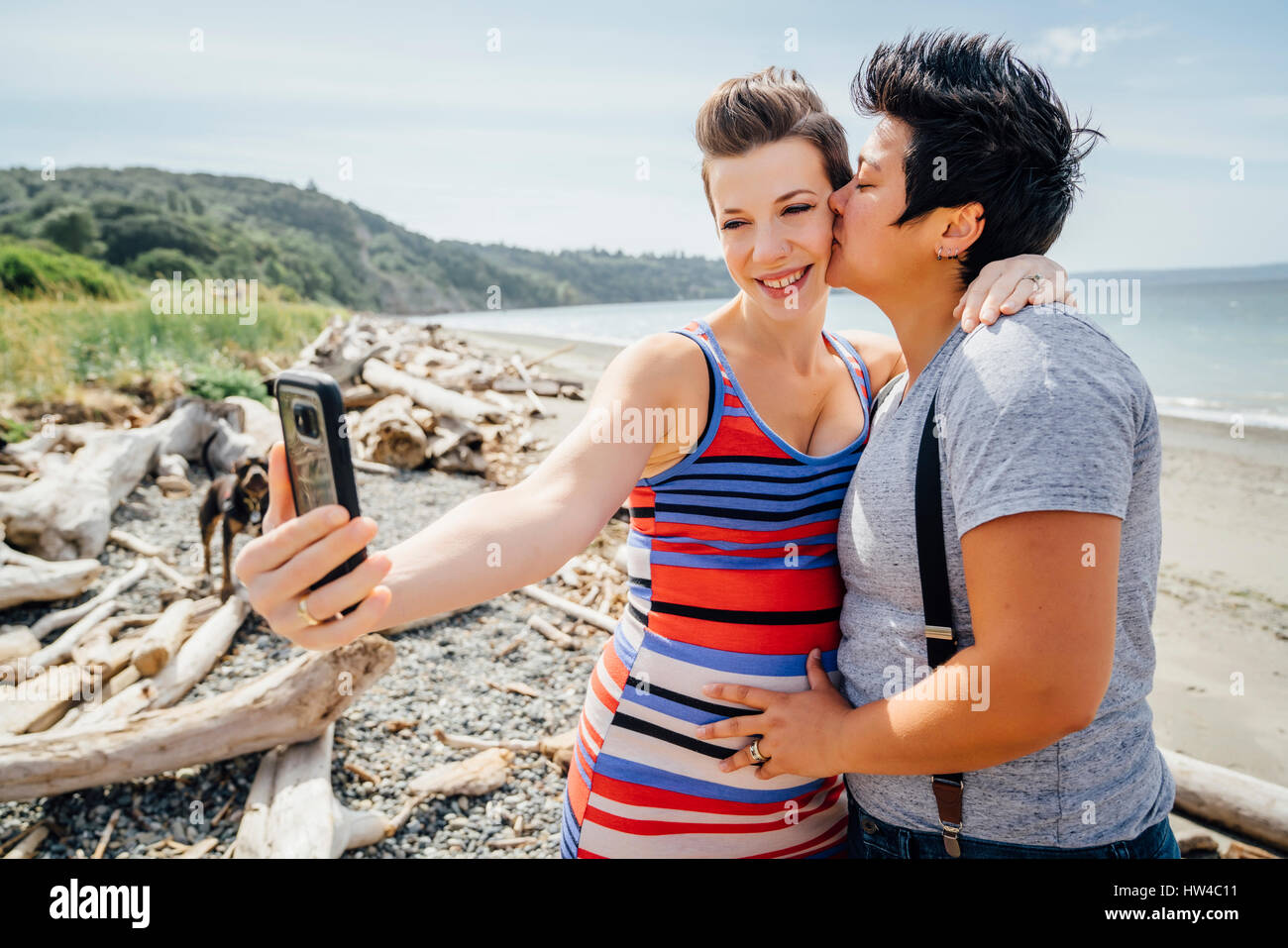 Pregnant lesbian couple posing for cell phone selfie on beach Stock Photo