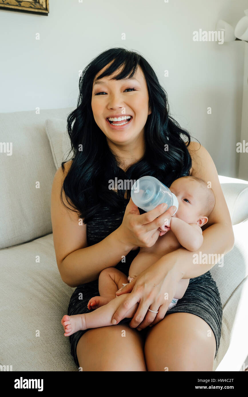 Portrait of smiling mother feeding bottle to baby daughter Stock Photo