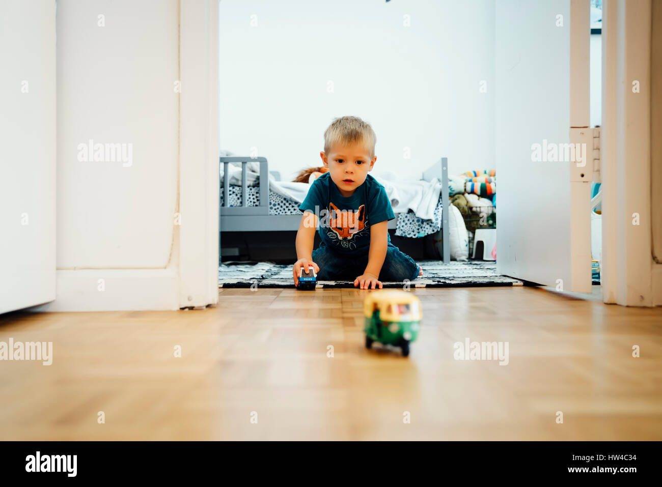 Boy kneeling on floor pushing toy cars Stock Photo
