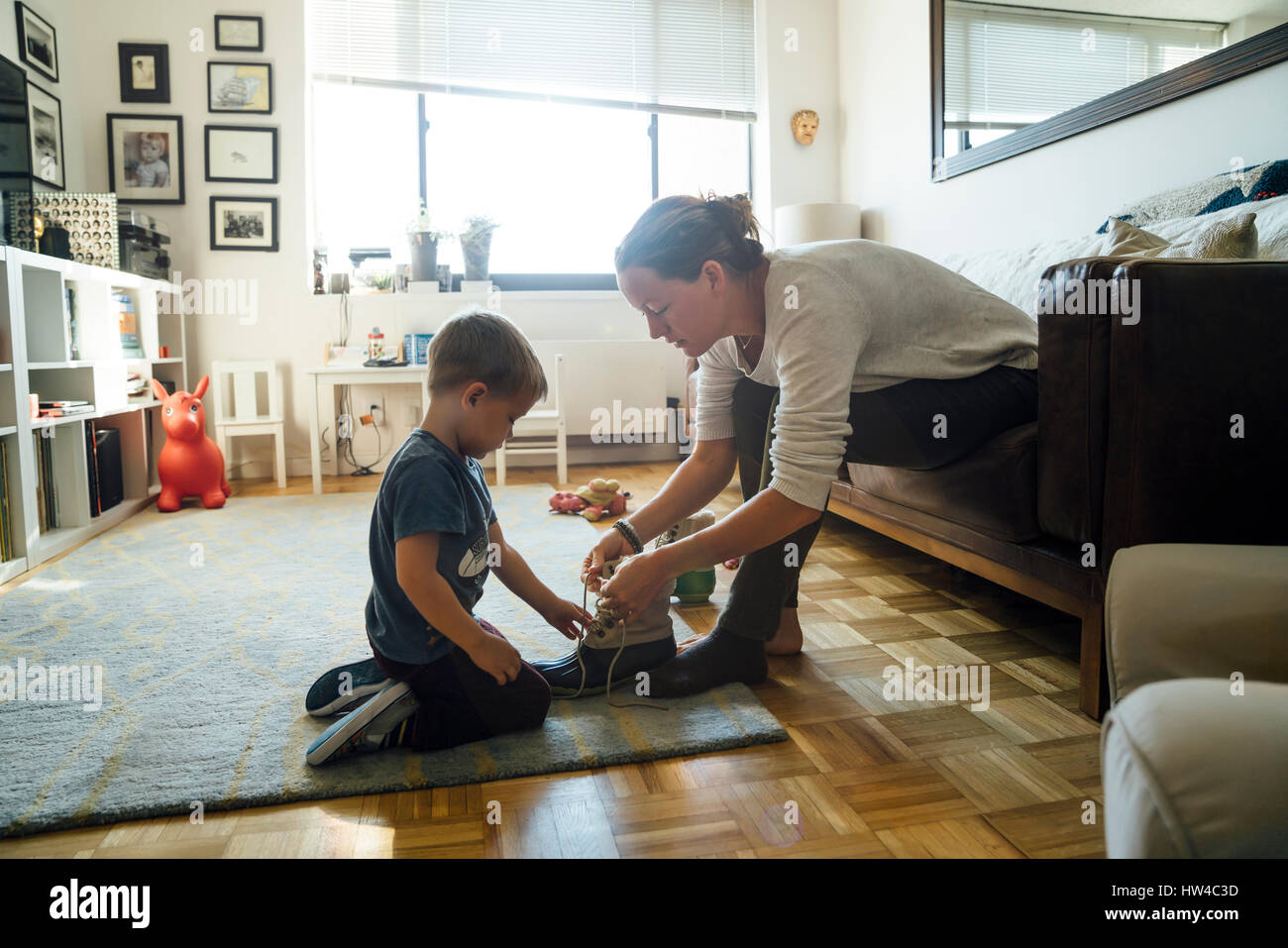 Mother teaching son to tie shoelace Stock Photo