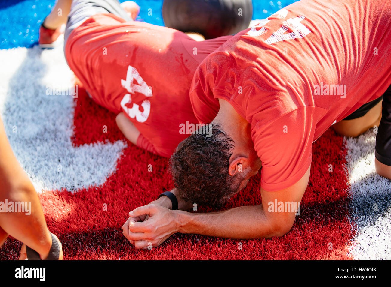 Fatigued men resting on artificial turf field Stock Photo