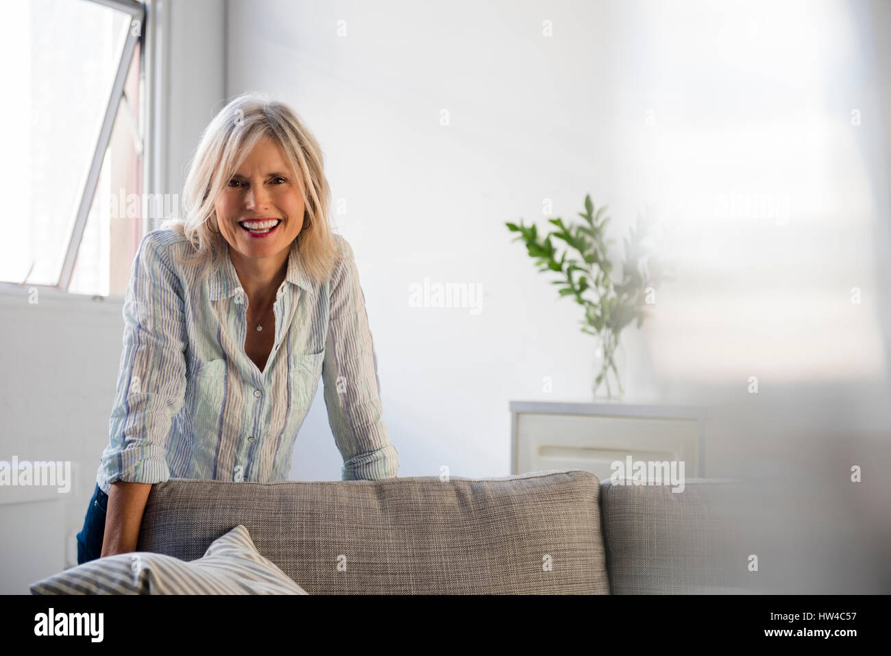 Smiling Caucasian woman leaning on sofa Stock Photo