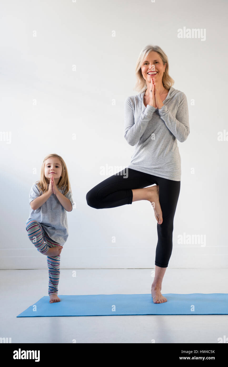 Caucasian granddaughter imitating grandmother practicing yoga Stock Photo