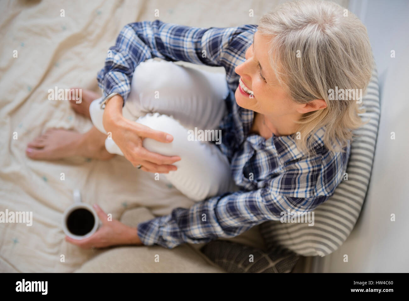 Caucasian woman sitting on bed drinking coffee Stock Photo