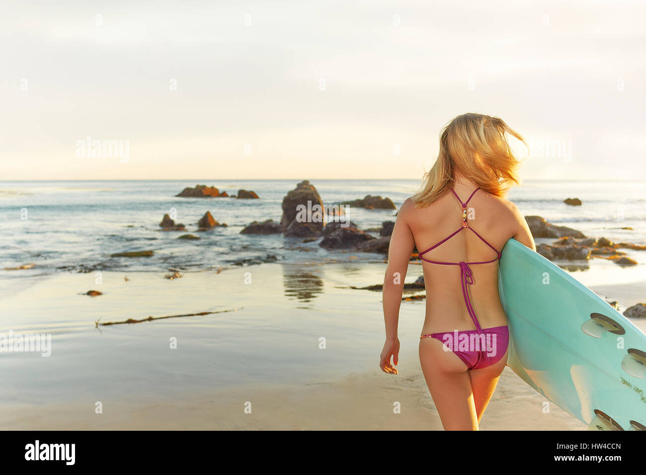 Caucasian woman carrying surfboard on beach Stock Photo