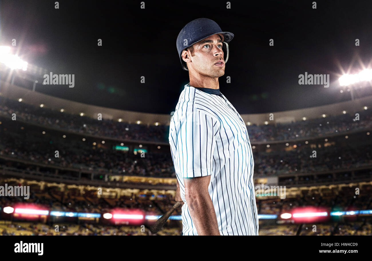 Mixed race baseball player standing in stadium Stock Photo