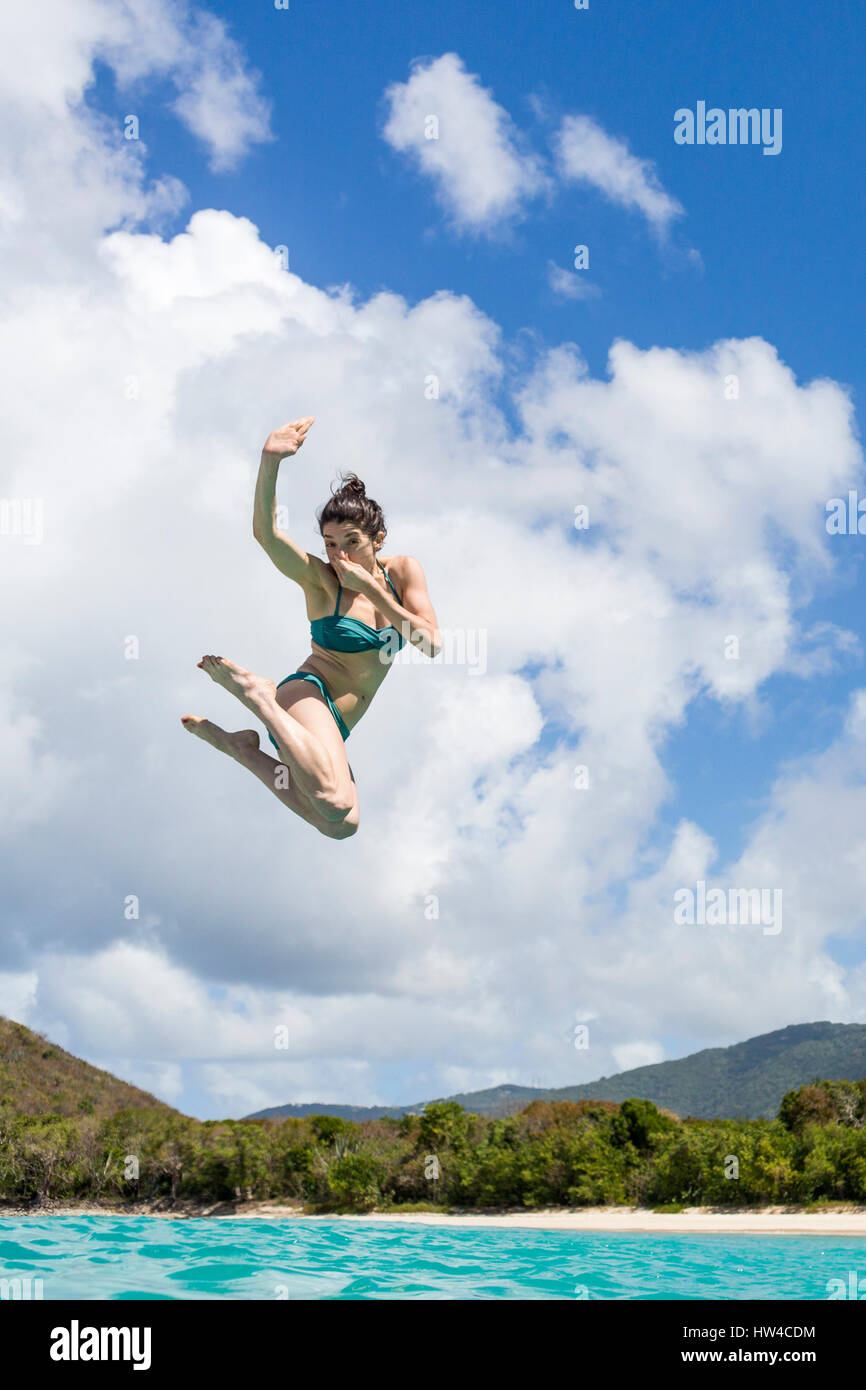 Caucasian woman jumping into tropical ocean Stock Photo