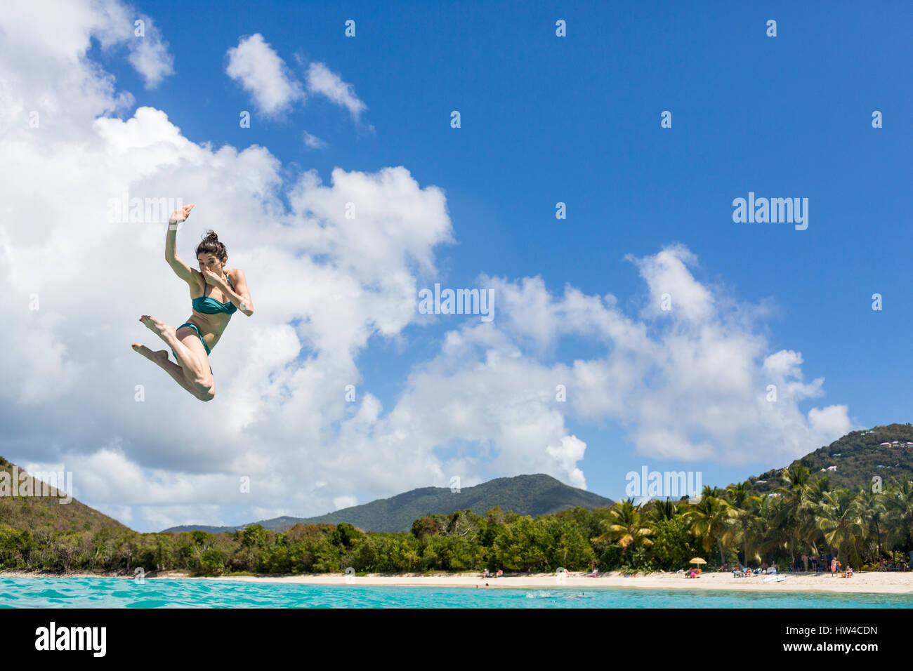 Caucasian woman jumping into tropical ocean Stock Photo