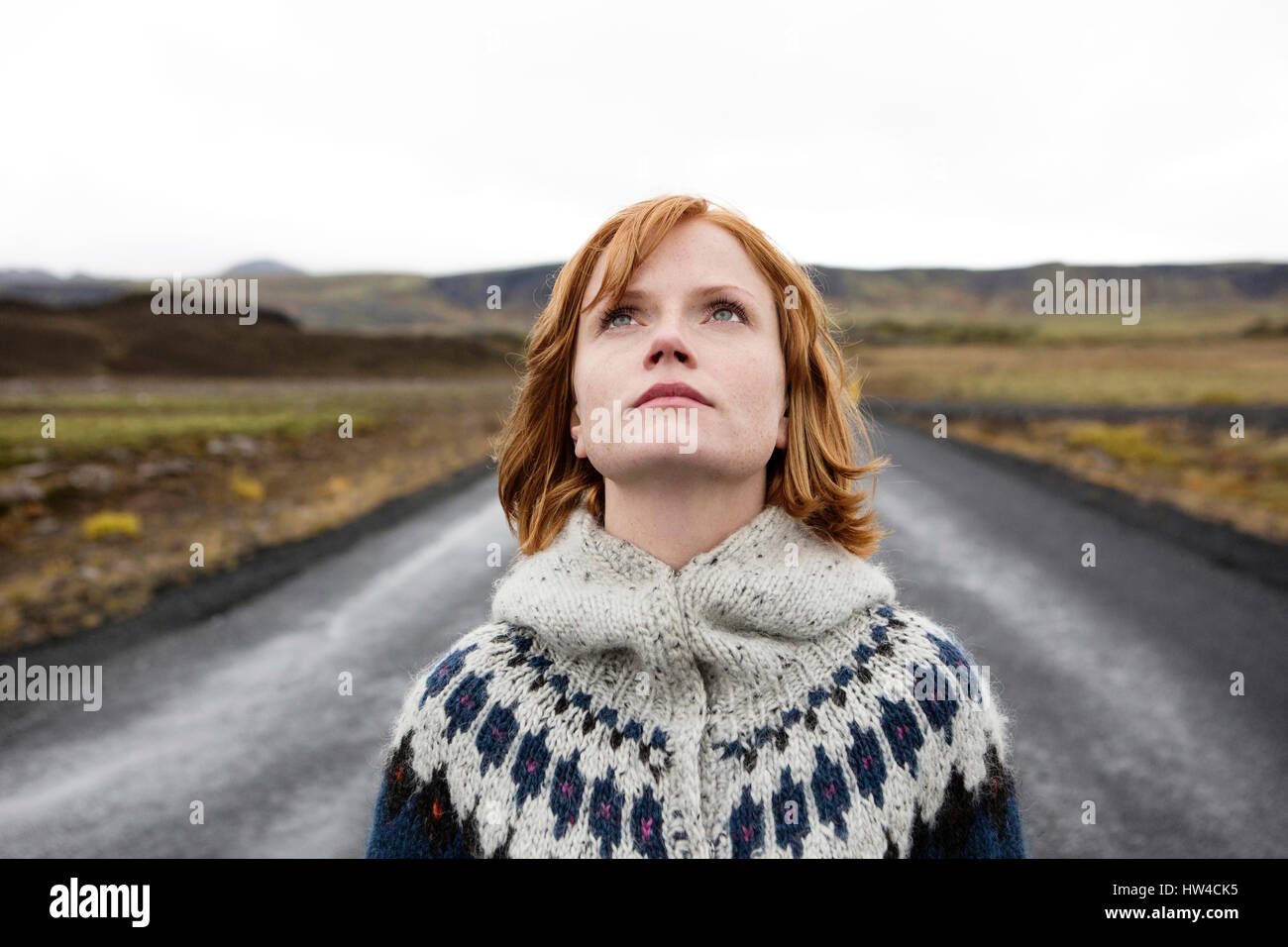 Caucasian woman wearing sweater in road looking up Stock Photo