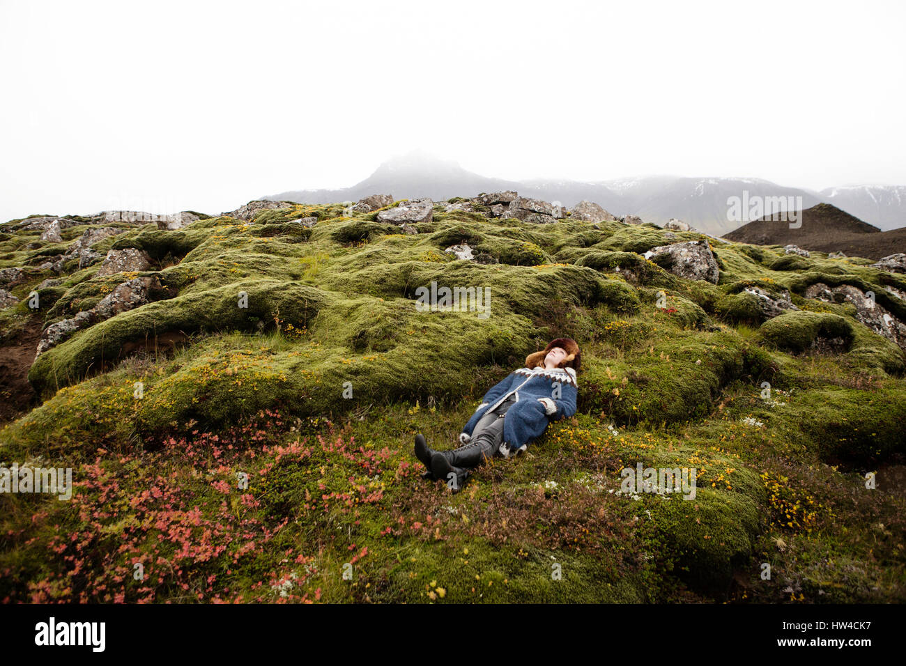 Caucasian woman laying on mossy rocks Stock Photo