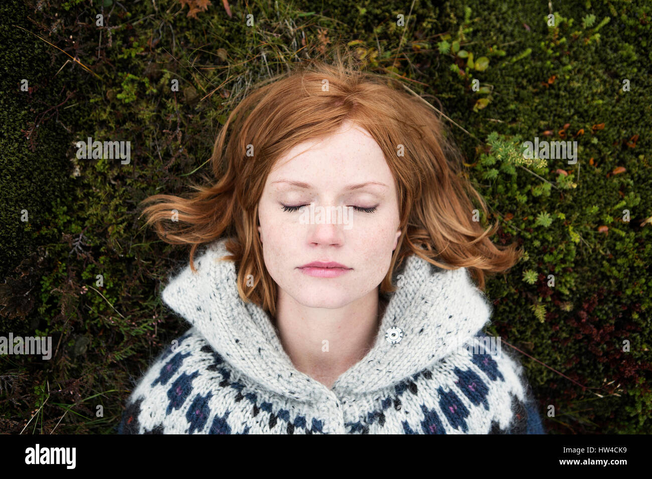 Caucasian woman laying on moss with eyes closed Stock Photo
