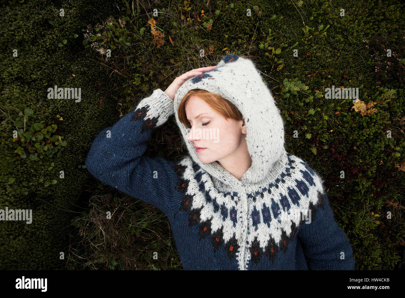 Caucasian woman wearing sweater laying on moss Stock Photo